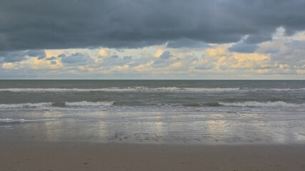 Belgian northsea coast with reflection of clouds in the water and wet sane