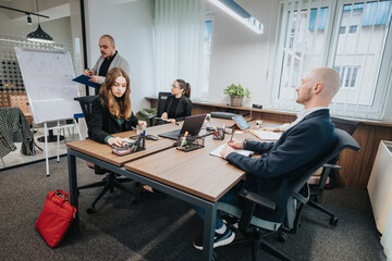 Office team engaged in a team meeting, discussing work tasks, and collaborating on projects in a corporate setting for brainstorming purposes.