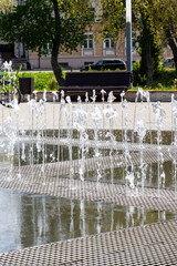 A beautiful fountain located in a park, accompanied by a bench in the background