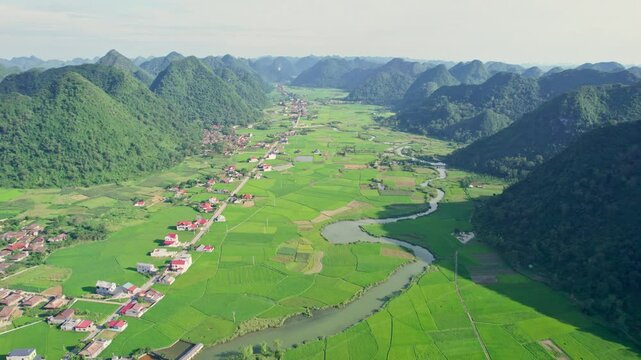 Scenic view Bac Son Valley with lush green rice field, mountain range, winding river and suburban village in countryside