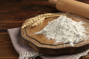 Pile of flour, spikes and rolling pin on wooden table, closeup