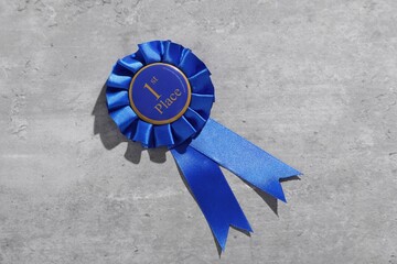 Blue award ribbon on light grey table, top view