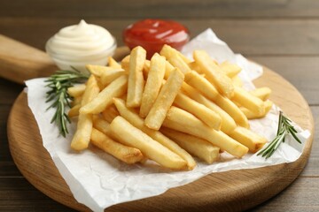 Tasty french fries with ketchup and rosemary on wooden table, closeup