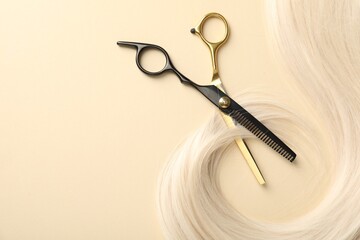 Hair lock and scissors on beige background, flat lay. Space for text