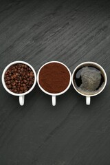 Aromatic ground coffee, beans and hot drink on black table, flat lay