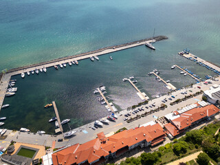Aerial view of Sveti Vlas, a Bulgarian seaside resort town with a marina, beaches, red-roofed buildings, and green hills. Popular summer destination on the Black Sea coast