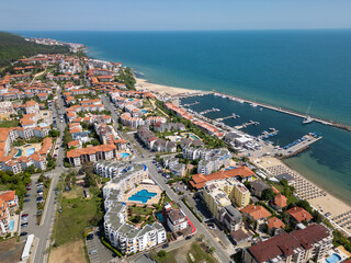 Aerial view of residential and resort buildings with red roofs in Sveti Vlas, Bulgaria. Sunny day, pools, gardens, and mountains in the background. Popular Black Sea vacation destination