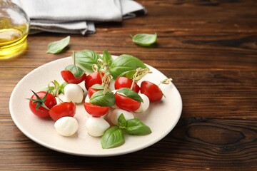 Appetizers with mozzarella, tomatoes and basil on wooden table