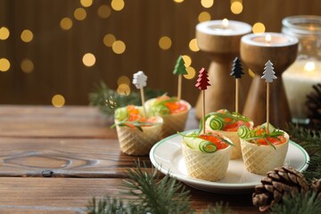 Tasty canapes and festive decor on wooden table against blurred lights, closeup. Space for text