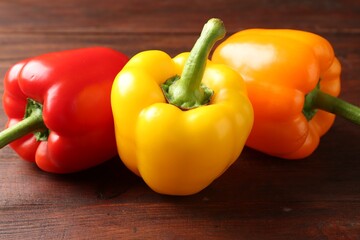 Ripe colorful bell peppers on wooden table, closeup