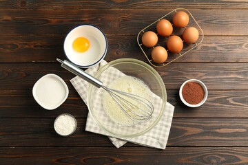 Making whipped cream. Bowl, whisk and ingredients on wooden table, flat lay