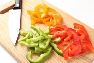 Slices of fresh colorful bell peppers and knife on white table, closeup