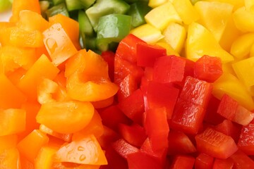 Pieces of fresh colorful bell peppers with water drops as background, closeup
