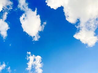Bright blue sky with fluffy white clouds on a sunny day. Ideal natural background for weather, freedom, tranquility, and outdoor themes