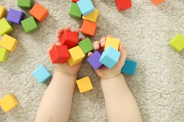 Naklejka premium Cute little child playing with colorful cubes at home, above view