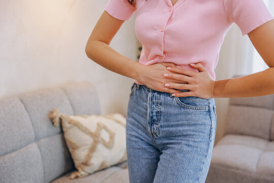 Young woman suffering abdominal pain, holding belly with hands