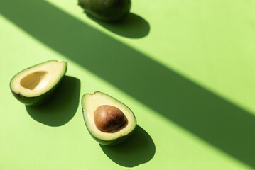 Avocado fruit cut on half on the green table background. Top view