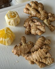 Fresh ginger roots and sliced lemon on a white cutting board, perfect ingredients for a healthy drink or natural remedy