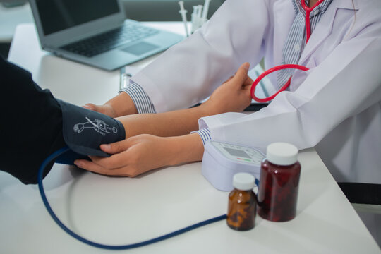 Female doctor gives advice and explains to patient for annual health check in examination room by measuring blood pressure and taking basic history. Health care and medicine concept.