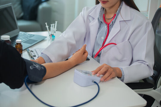 Female doctor gives advice and explains to patient for annual health check in examination room by measuring blood pressure and taking basic history. Health care and medicine concept.
