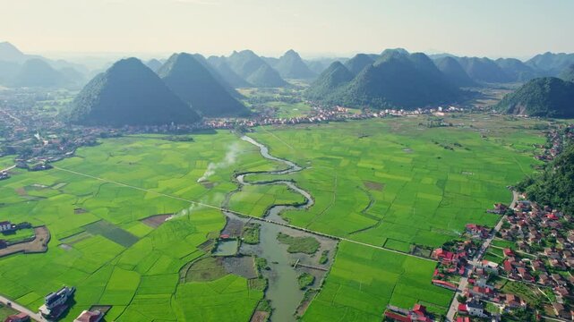 Scenic view Bac Son Valley with lush green rice field, mountain range, winding river and suburban village in countryside