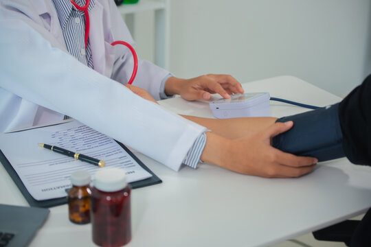 Female doctor gives advice and explains to patient for annual health check in examination room by measuring blood pressure and taking basic history. Health care and medicine concept.
