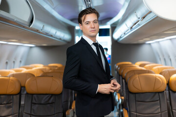 Portrait businessman in suit in plane during business trip. portrait of handsome confident steward near cozy chair of passenger aircraft