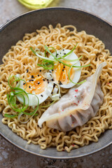 Ramen noodles with steamed dumpling, boiled egg and spring onion, vertical shot, middle close-up