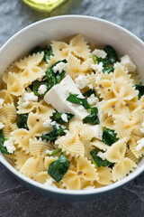 Spanakopita pasta or farfalle with feta cheese and wilted spinach, close-up, vertical shot
