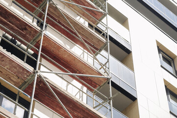 Scaffolding on modern building. Construction site facade. Renovation of urban architecture. Safety platform structures. Metal framework and platforms. Apartment block repairs. Exterior maintenance. © Paweł Michałowski