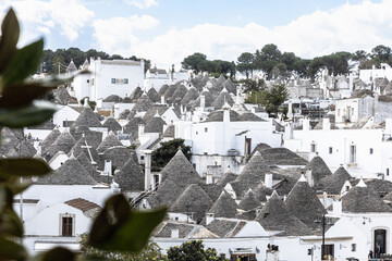 Traditional Street in Alberobello with Multiple Trulli Houses and Clear Blue Sky in Puglia, Italy