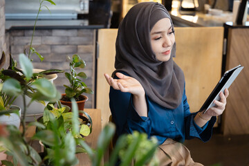 Asian female Muslim Digital Nomad Worker working remotely in cafe, feeling bad for the mistake and failure