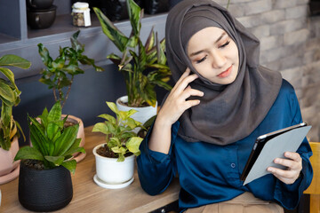 Asian female Muslim Digital Nomad Worker working remotely in cafe with stressed expression, bad and tired feeling