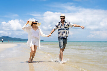 Couple enjoys a sunny day by the beach while walking hand in hand near the water