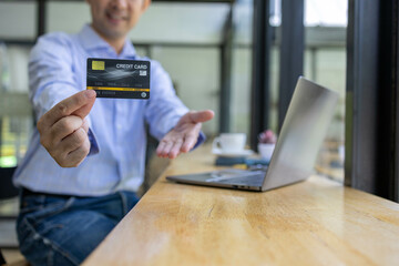 A man is using a laptop to pay for something with a credit card. Concept of convenience and ease, as the man is able to complete his transaction quickly and easily using his laptop
