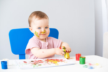 child is drawing on white sheets with finger paints