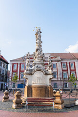 Fototapeta premium Detailed view of a tall, ornate stone monument adorned with multiple figures and sculptures, standing prominently in Timisoara's historic Liberty Square, Romania.