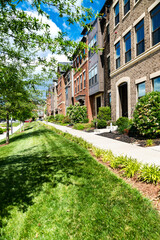 Apartment building with green lawn and long sidewalk along the wall.