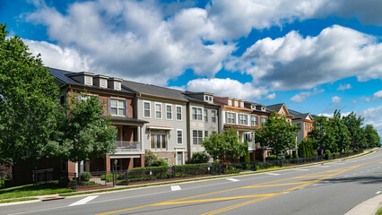 street in a residential neighborhood in the suburbs. Rows of apartment buildings with lawns along...