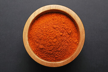 Aromatic paprika powder in bowl on dark table, top view