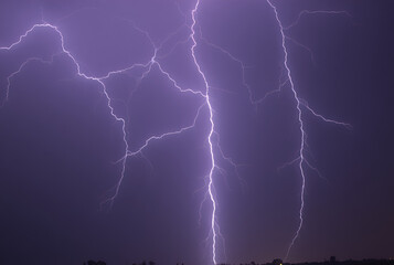Intense thunderstorm with bright lightning illuminating the dark sky, perfect for dramatic weather scenes. Not photography of real event.