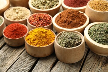 Different aromatic spices in bowls on wooden table, closeup