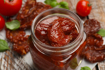Tasty sun dried tomatoes and fresh vegetables on wooden table, closeup