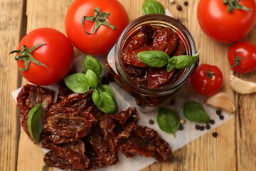 Tasty sun dried tomatoes, fresh vegetables and peppercorns on wooden table, flat lay