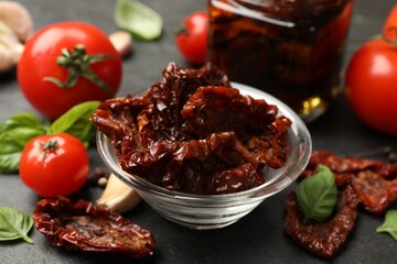 Tasty sun dried tomatoes and fresh vegetables on black table, closeup