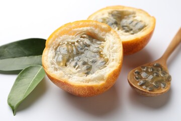 Ripe passion fruit, seeds and green leaves on white background, closeup