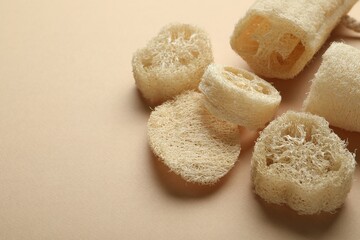 Natural loofah sponges on beige background, above view. Space for text