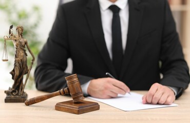 Judge working, Lady Justice figure and gavel on desk indoors, selective focus