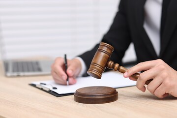 Judge with gavel working at desk indoors, closeup