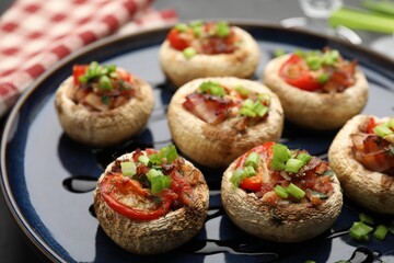 Tasty stuffed mushrooms served on black table, closeup